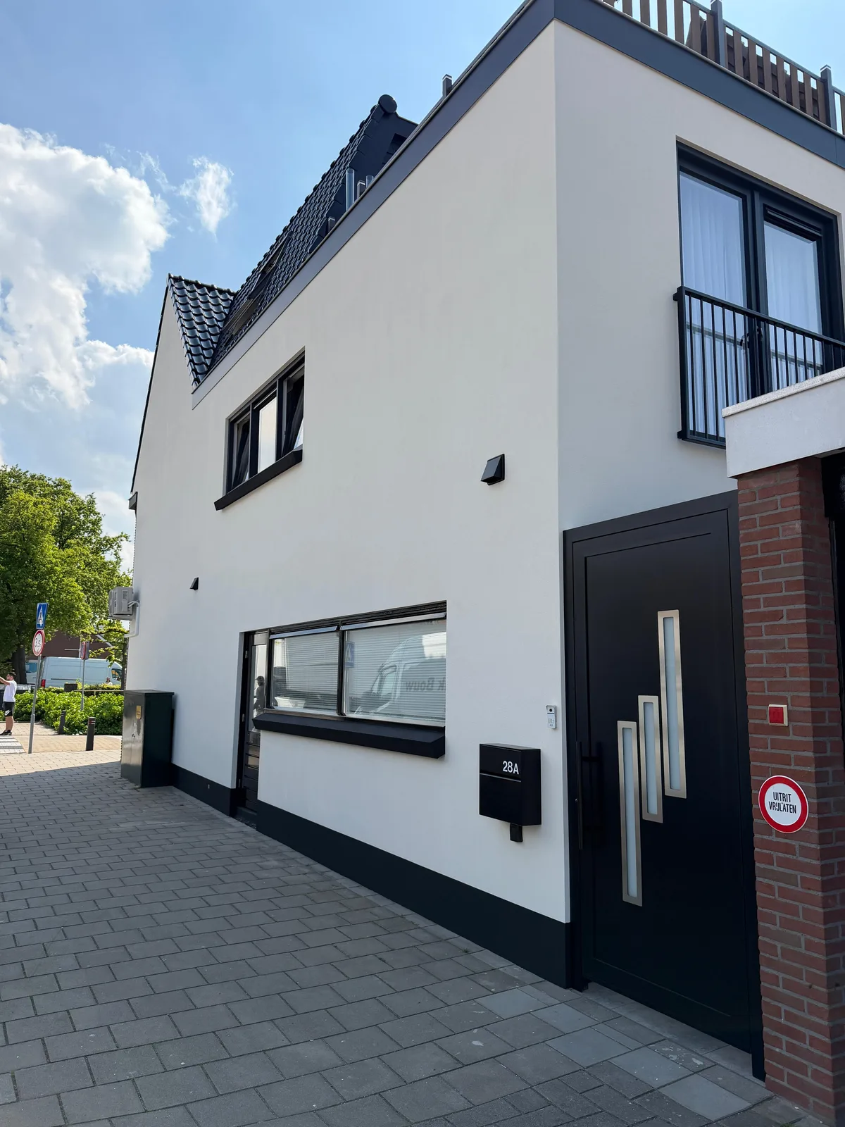 Wit gestuukte woning met zwarte kunststof kozijnen, een garage en een balkon