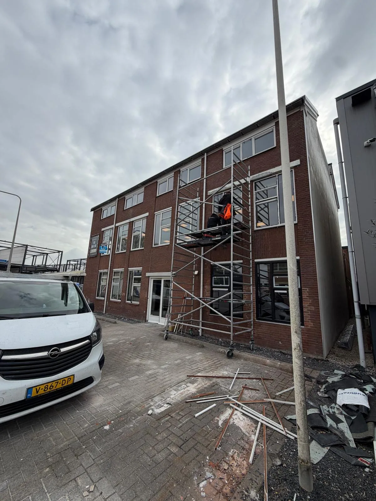 Bakstenen bedrijfspand met een steiger langs de gevel tijdens het onderhoud