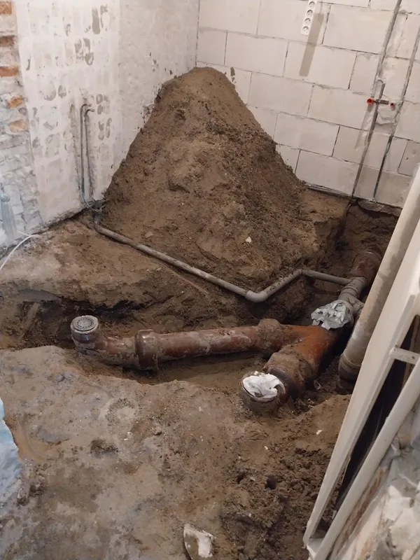 Opengegraven vloer met nieuw aangelegde rioolbuizen en leidingen